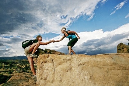 Bild für den Systemischer Business Coach Ausbildung. Zwei Frauen beim klettern. Eine hilft der anderen hinauf